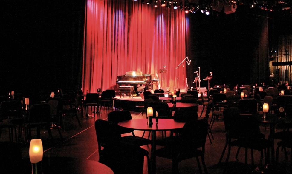 An image of the Carpenter Center Cabaret Stage showing instruments on a stage surrounded by candle lit tables.