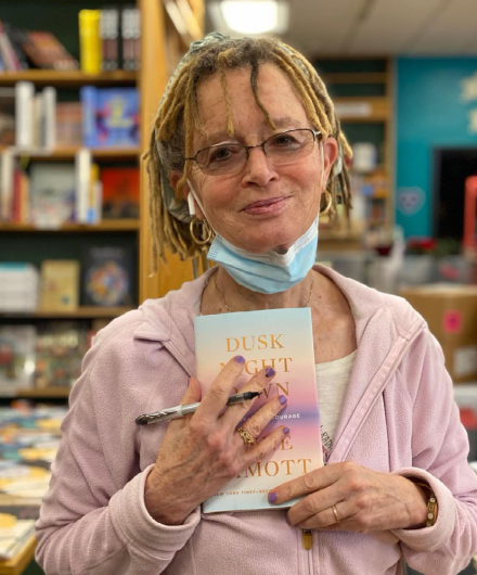 Anne Lamott holding a copy of her new book at a bookstore.
